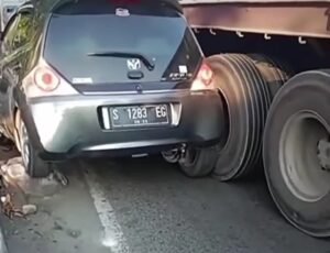 Sebuah Mobil Terjepit di Antara Truk dan Pembatas Jalan